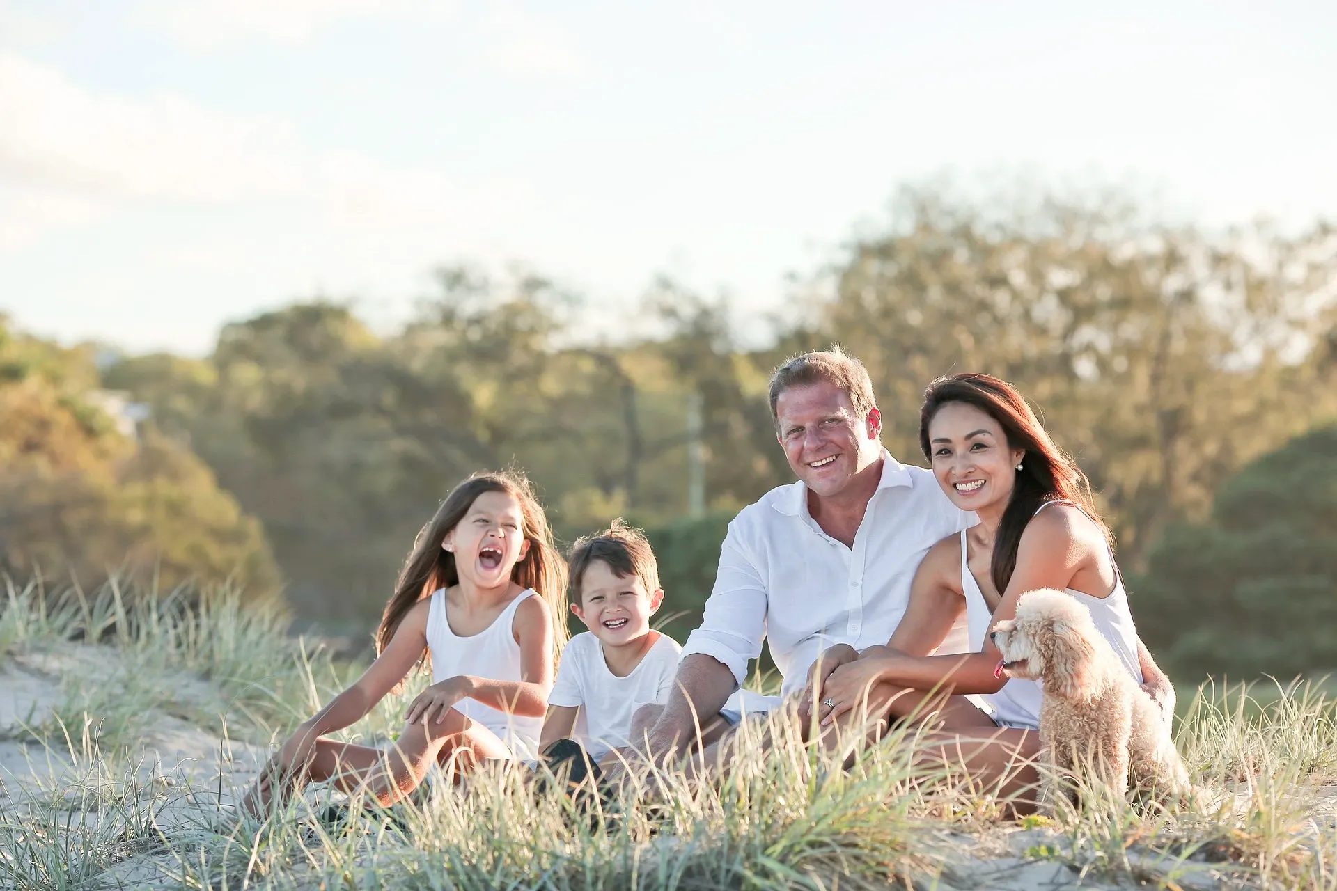 An einem sonnigen Tag sitzt eine fröhlichen Familie gemeinsam auf einem Deich.